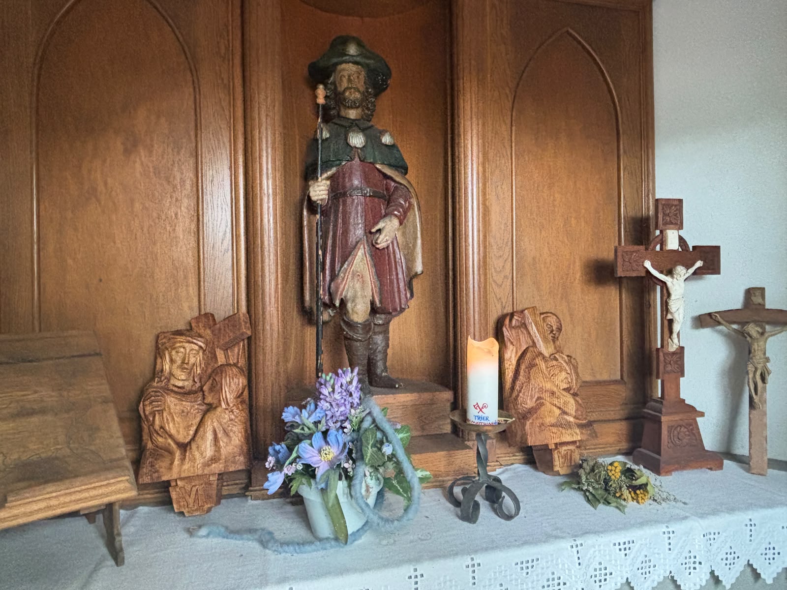 Ein Blick auf Figuren, Blumen und Kerze im Inneren einer Kapelle., vergrößern