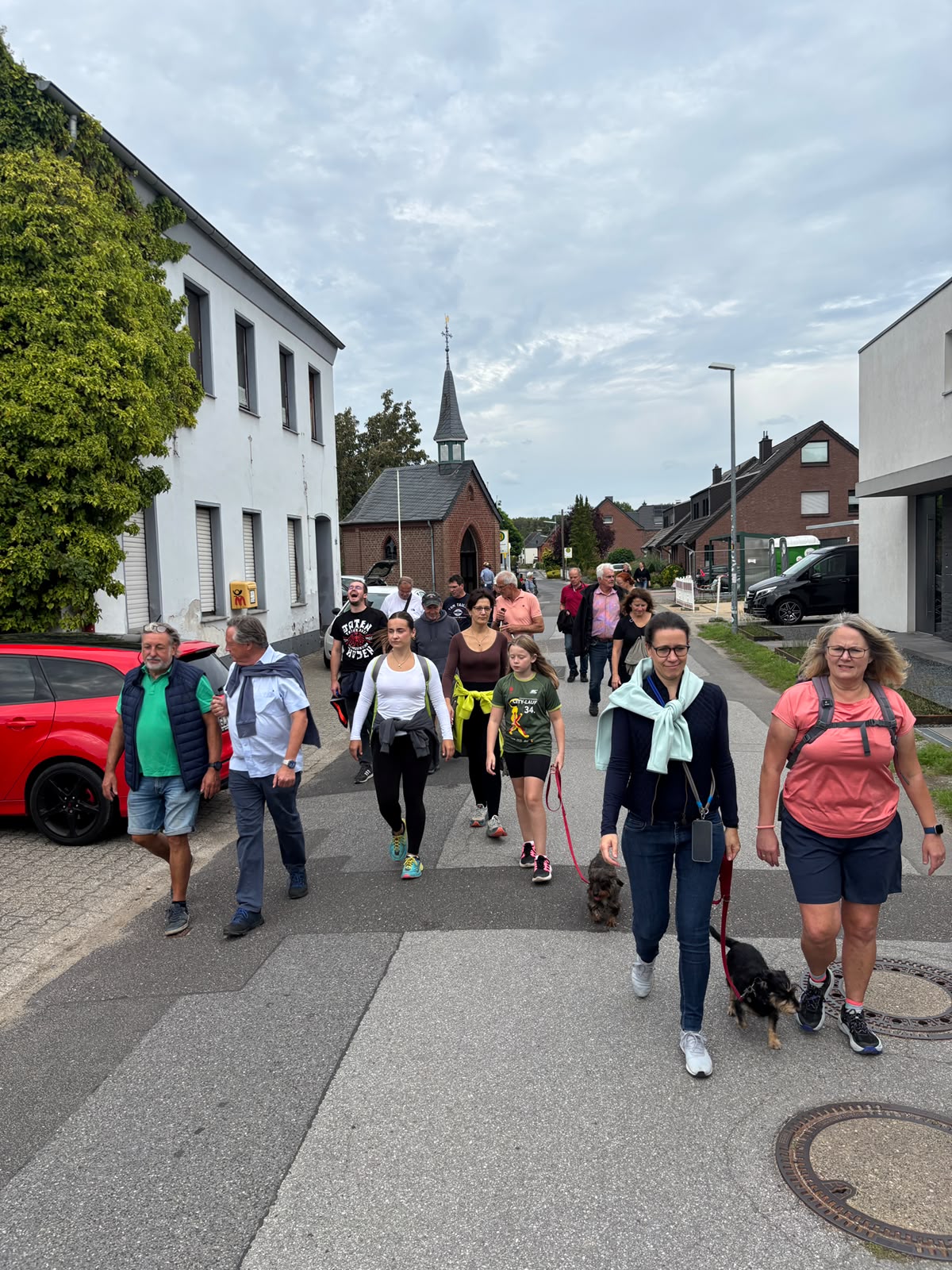Teilnehmerinnen und Teilnehmer wandern durch den Ort; im Hintergrund ist die Marienkapelle zu sehen., vergrößern