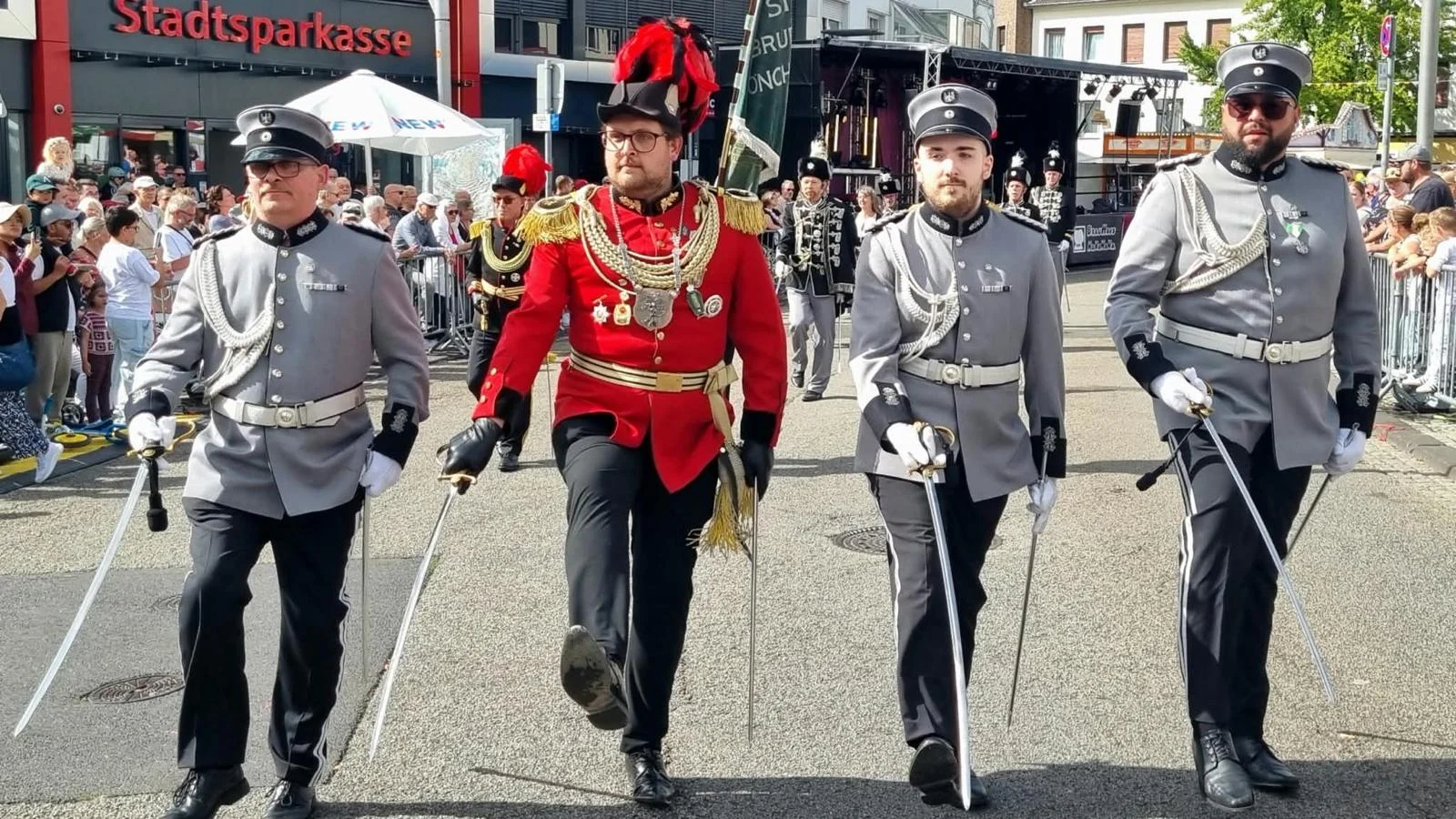Schützen in grauen und roten Uniformen bei der Parade, vergrößern